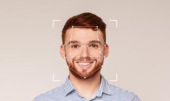 A smiling man is shown in front of a plain background with facial recognition technology overlay. This technology highlights key facial features for identification purposes. photo