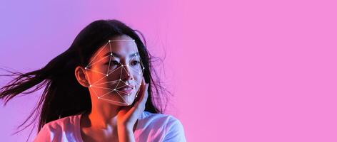 A woman models facial recognition technology with a highlighted facial mapping design. The background features vibrant colors, creating a modern atmosphere that emphasizes technology use. photo