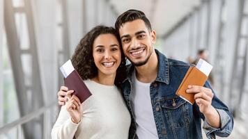 Happy Travellers. Portrait Of Young Arab Couple With Passports And Tickets Posing At Airport, Cheerful Smiling Middle Eastern Spouses Enjoying Travelling Together, Ready For Vacation Trip, Closeup photo