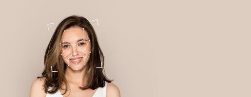 A smiling young woman is featured with facial recognition markers overlayed. The background is plain, allowing focus on her expression and the technology used for identification. photo