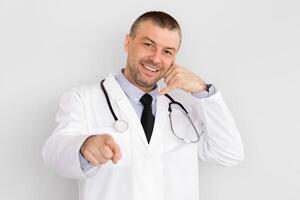 Better Call Doctor. Portrait of mature smiling male doctor showing call me gesture isolated over white background photo