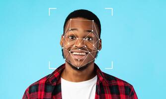 A young man smiles widely as facial recognition technology highlights his features against a blue background. His expression conveys confidence in this modern technology setting. photo