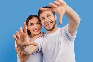 Creative Vision. Portrait of excited couple posing together, framing faces with hands, isolated on purple studio wall photo
