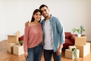Love, Young Family And New Home. Portrait Of Happy Young Spouses Hugging And Posing Looking At Camera After Moving, Relocating To New Apartment Standing In Living Room. Mortgage And Ownership Concept photo