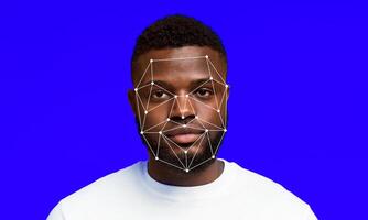A man stands against a bright blue background, while a facial recognition technology overlays map points on his face. The display showcases advancements in identification systems and methods. photo