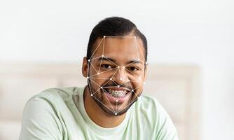 A smiling person with braces displays facial recognition technology applied to their face. The background features an empty space, enhancing focus on the subject's expression and identification. photo