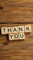 Scrabble letters spell out thank you on a wooden table, expressing gratitude and appreciation photo