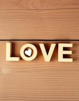 Decorative wooden letters spelling love on a rustic wooden surface with a heart shape cutout photo