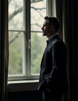 Contemplative businessman gazing out window in dimly lit room for reflective mood design photo