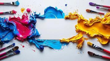 Vivid paint splashes in blue pink and yellow create engaging artistic setting. Brushes and paint tubes are scattered edges enhancing creative vibe photo