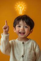 A little boy is holding up his finger with an idea light bulb above his head photo