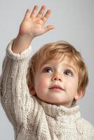 A young boy in a sweater is reaching up photo