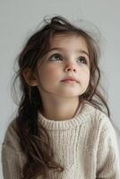A little girl in a sweater looking up photo