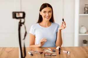 Beauty Blogging. Woman Making Makeup In Front Of Camera Creating Tutorial Sitting At Home. Selective Focus photo