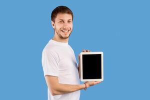 Cool Application Concept. Smiling man holding tablet, showing black blank screen, empty space, mock up photo