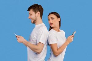 Distrust Concept. Jealous wife spying on husband while he using phone, looking over the shoulder, standing back to back photo