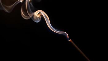 A tendril of incense smoke rising against a stark black background with a glowing ember photo