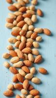 A scattering of whole almonds on a light blue wooden surface creating an organic pattern photo