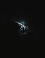 Solitary Figure Walks Along a Craggy Path Lit by an Eerie Light in the Night photo