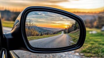 Scenic sunset road reflecting in car mirror during autumn road trip photo