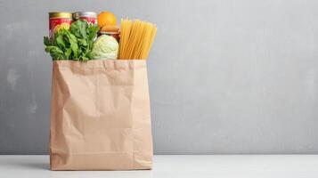 grocery items in paper bag on white table gray wall. food with fresh vegetables canned goods copy space for your text photo