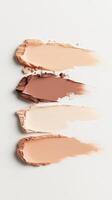 Foundation samples blending across white surface, displaying gradient makeup palette for cosmetic compact powder design and artistic color transition photo