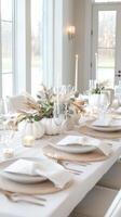 Minimalist autumn table setting with white pumpkins, candles, and eucalyptus leaves creating a cozy atmosphere photo