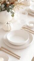 Minimalist autumn table setting with white pumpkins, candles, and eucalyptus leaves creating a cozy atmosphere fall photo