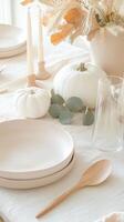 Minimalist autumn table setting with white pumpkins, candles, and eucalyptus leaves creating a cozy atmosphere Thanksgiving photo