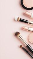 Makeup brushes, lipstick, highlighter, and blush scattered artfully on soft pink surface, modern beauty product arrangement Copy space for text photo