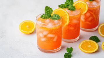 Chilled orange lemonade glasses displaying sparkling ice cubes, fresh orange segments, bright mint leaves creating summery beverage refreshment food healthy eating concept photo