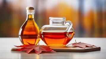 A glass pitcher and bottle of amber liquid on a wooden cutting board with red leaves photo