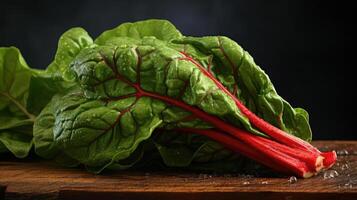 A close-up photograph of a leafy green vegetable with red veins on a wooden table photo