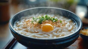 A bowl of steaming hot noodles with an egg and chopped green onions on top photo
