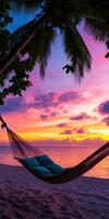 The hammock is hanging over the ocean with a beautiful sunset photo