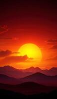 A beautiful sunset over a mountain range with a large yellow sun in the sky photo