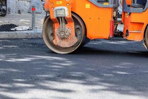 A fragment of the work of a road roller for asphalt compaction on a summer day. photo