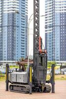 A construction platform on a caterpillar track for lifting loads to a height against the backdrop of high-rise residential buildings. photo