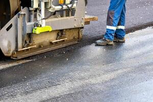 A fragment of the work of a road paver to renew the asphalt on the road on a summer day. photo