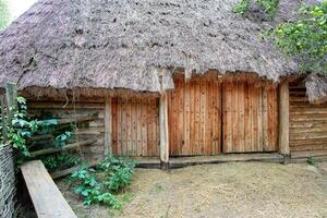 Rustic charm of an ancient thatched roof cottage nestled in a lush green landscape photo