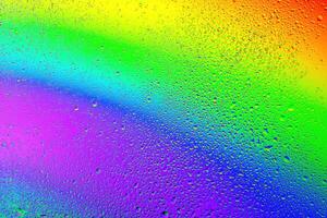 Colorful droplets create a stunning rainbow effect on a misty surface in sunlight photo