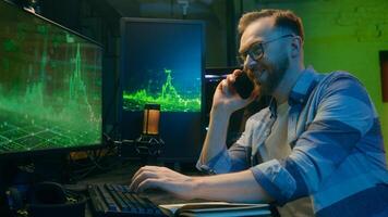 Smiling happy Caucasian broker man guy developer crypto businessman discussing mobile phone at home neon trader male work computer nighttime freelancer business good result thumb up sign stock trade photo