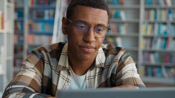 Bored African American man male guy tired fatigue overworked library high school university diploma challenge task homework student laptop e-learning desktop computer working deadline cyberspace web photo