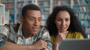 Happy African American man Arabian Latina woman using laptop computer technology device library high five project students learn task female male study educate enjoy connect internet knowledge clever photo