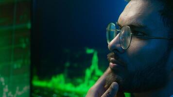 Indian Arabian man programmer hacker thinking looking computer chart guy trader analysis trading crypto currency database male technology IT specialist thoughtful coder monitor finance brainstorming photo