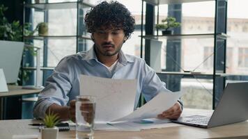 Focused businessman business person accountant office worker writing ideas in notebook paperwork Arabian Indian student write notes data information e-learning with laptop computer educational course photo