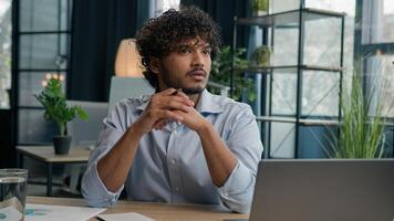 Thoughtful man Arabian Indian businessman employer manager working with laptop pensive thinking pondering idea solving business problem solution creative computer work in office consider think doubt photo