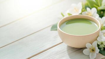 bowl of matcha tea surrounded by white flowers on wooden table photo