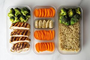 A flat lay of meal prep containers with grilled chicken, quinoa, broccoli, and carrots, showcasing a clean and balanced approach to healthy eating. . photo