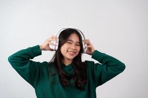 A happy attractive carefree pleased teenage girl has fun, relaxing dancing and smiling, joyfully with raised arms, being entertained and amused isolated on a white background. photo